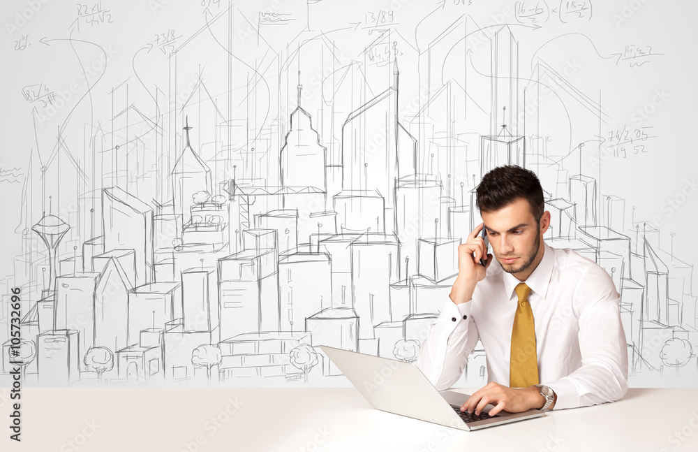 Businessman sitting at the white table with hand drawn buildings Businessman sitting at the white table with hand drawn buildings