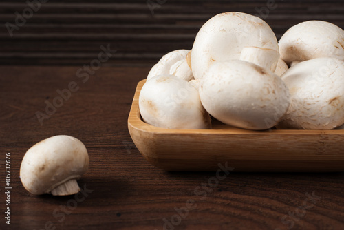 Fresh raw porcini boletus mushrooms in square bamboo bowl. Wood background
