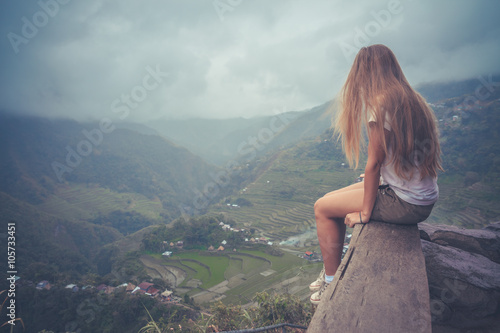 Freedom, travel,success or loneliness concept. Woman sitting on the bench looking at the breathtaking view of rice terraces. Highest view point from Batad rice terraces. Batad, Ifugao, Philippines.