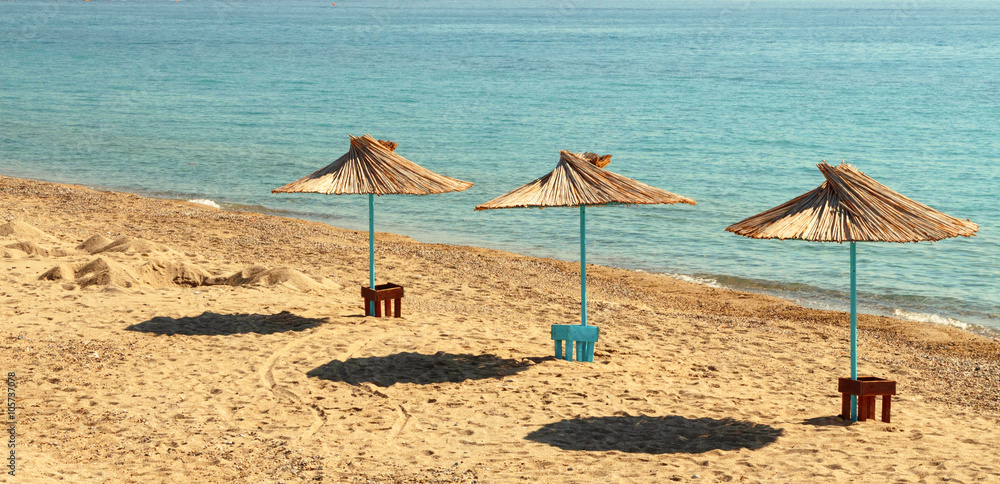 Fototapeta premium Three sun umbrellas by the beach