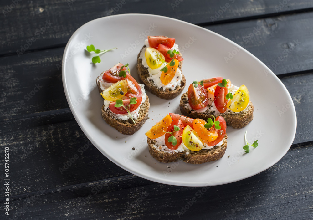 Tomato and cheese bruschetta on the ceramic plate on dark wooden background. Healthy breakfast, snack or appetizer with wine