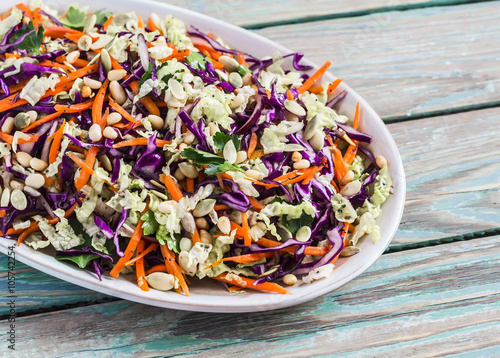 Fresh vegetable salad with red cabbage, carrots, sweet peppers, herbs and seeds. Healthy food, rustic style