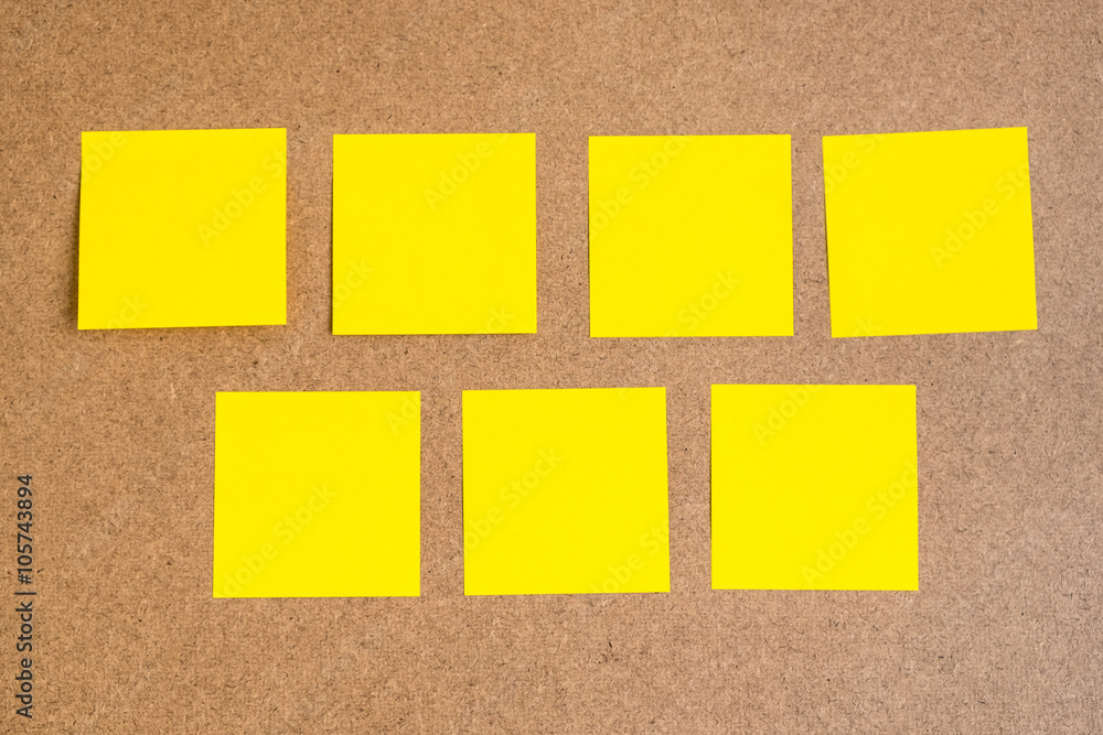 Fototapeta premium Seven black yellow sticky notes on brown wood board