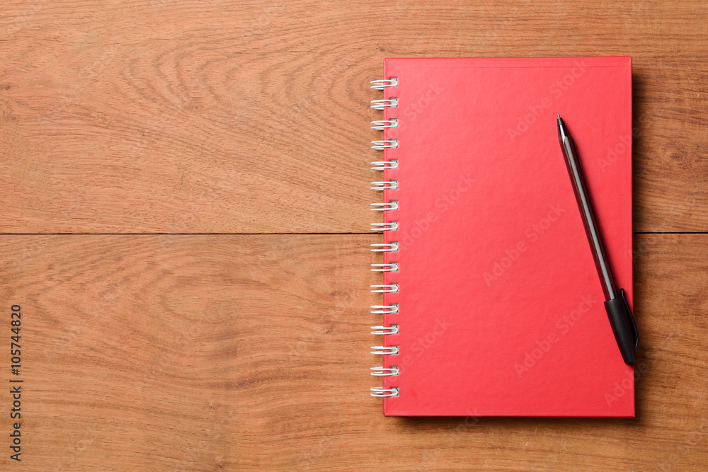 Red notebook with pen on wooden table Red notebook with pen on wooden table