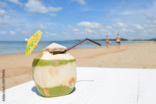 Coconut with drinking straw at the sea