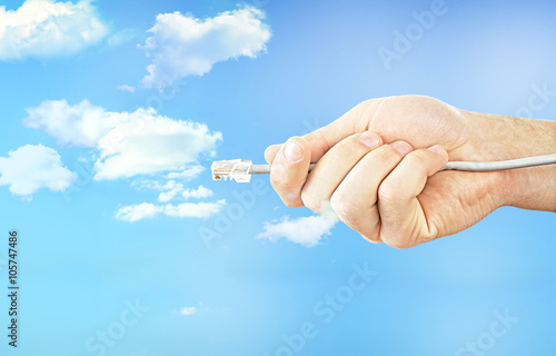 Internet cable in hand on blue sky background with cloud