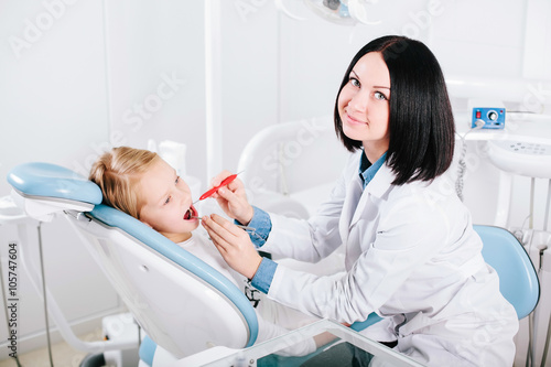 Young handsome dentist treats tooth child, a woman dentist