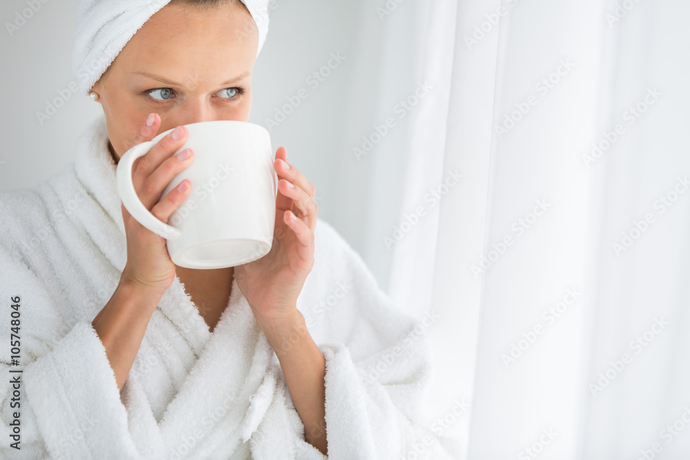 Gorgeous young woman wearing a bathrobe and enjoying a mug Gorgeous young woman wearing a bathrobe and enjoying a mug