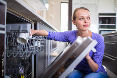 Housework  young woman putting dishes in the dishwasher