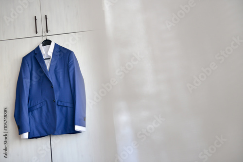 Blue suit hanged to a wood closet in natural light