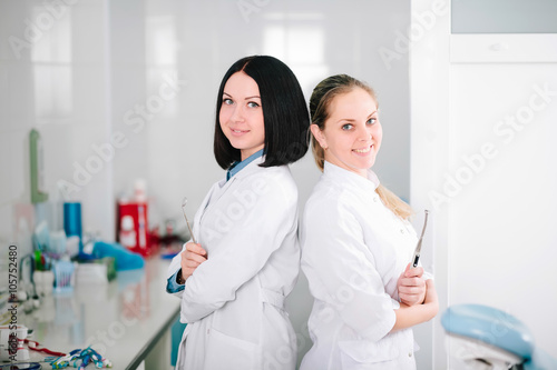 Young beautiful girls - dentist prepares the tooth to treat the patient.