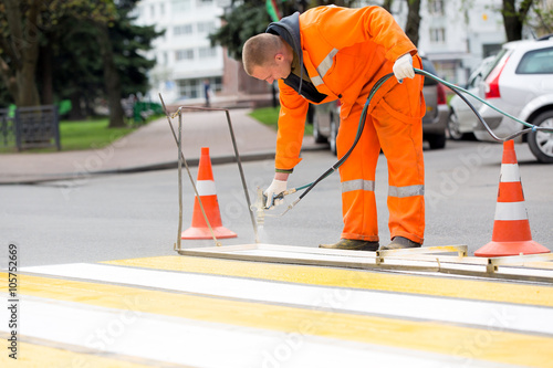 Road worker marking zebra crossing traffic sign using paint sprayer gun © Fotolia RAW