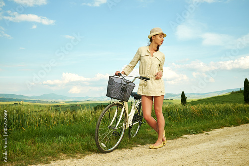 Foto Woman with vintage bike in a country road.