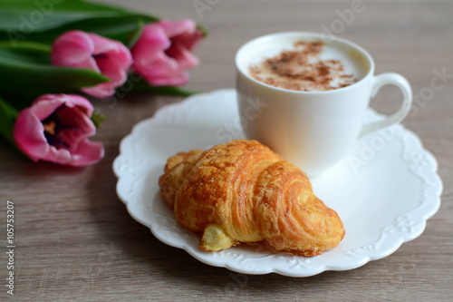 cup of coffee and yummy croissant with flowers