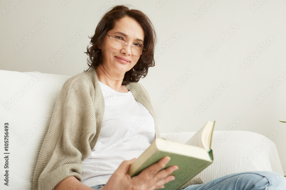 Charming mid age lady enjoying being at home and reading. Charming mid age lady enjoying being at home and reading.