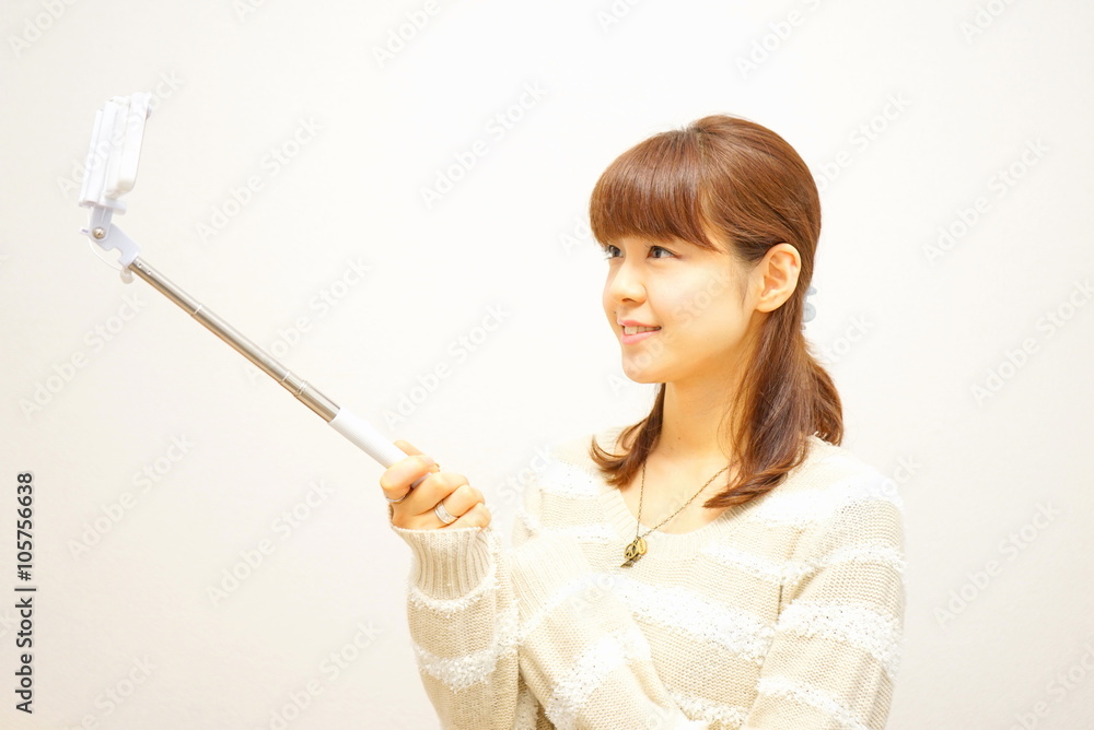 自撮り棒 セルフィー 自撮り セルカ 観光 女子 / Young woman using a selfie stick with her smartphone 自撮り棒 セルフィー 自撮り セルカ 観光 女子 / Young woman using a selfie stick with her smartphone