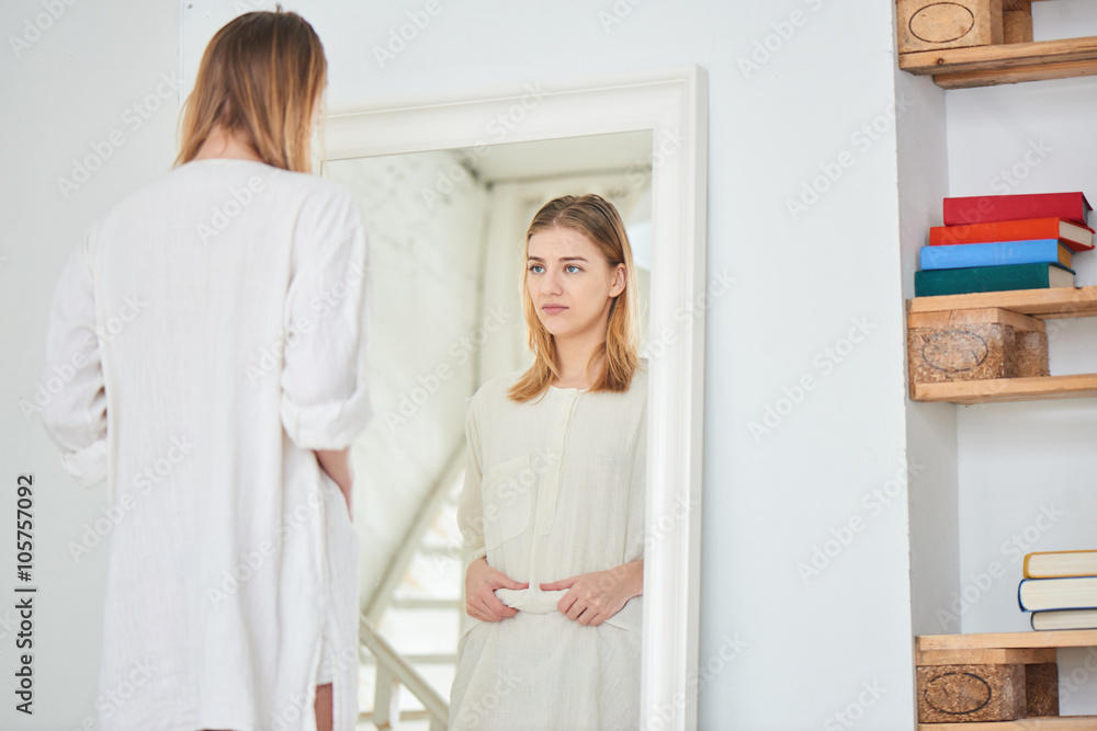 Girl unhappy with their appearance looks in the mirror Girl unhappy with their appearance looks in the mirror