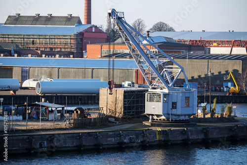 Photo cargo port scene with an old dockyard crane on the pier.