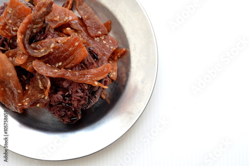 black sticky rice with fried sliced pork ,sesame , black pepper on metal dish