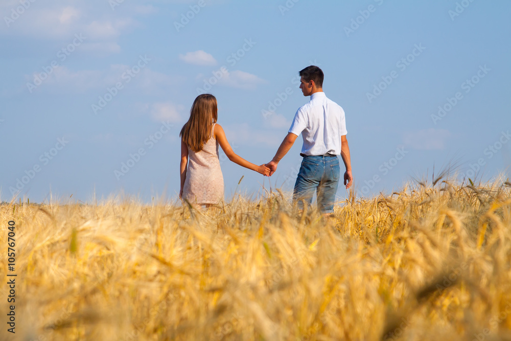 Young couple walking through wheat field Young couple walking through wheat field