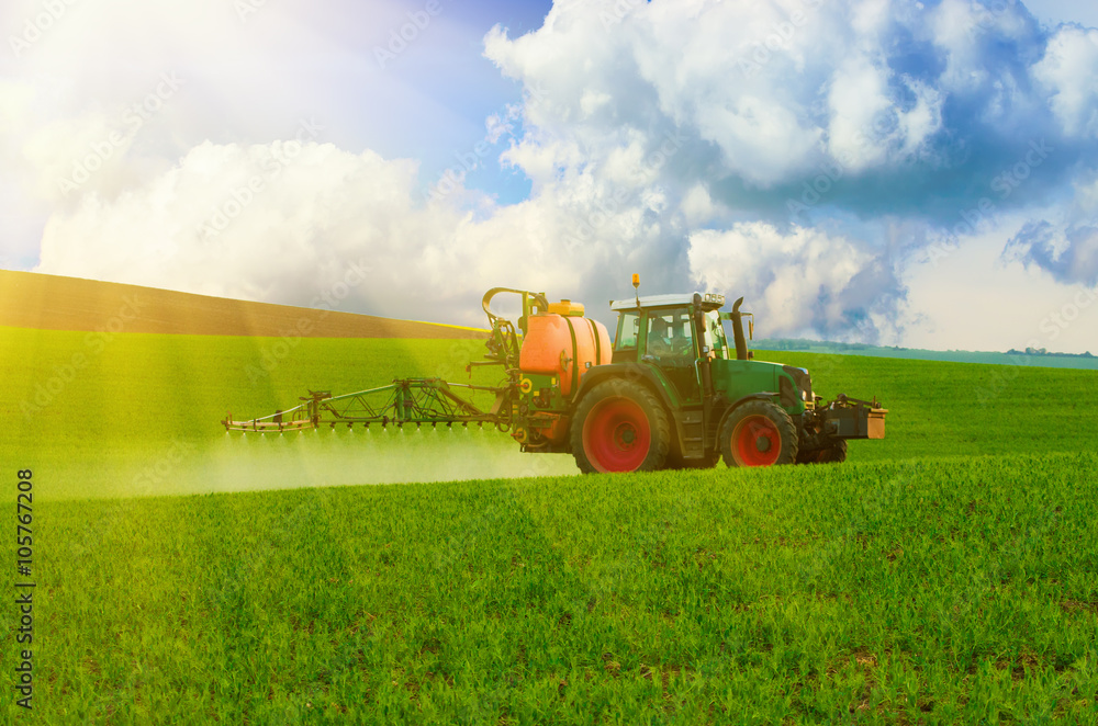 Obraz premium Farm machinery spraying insecticide to the green field, agricultural natural seasonal spring background
