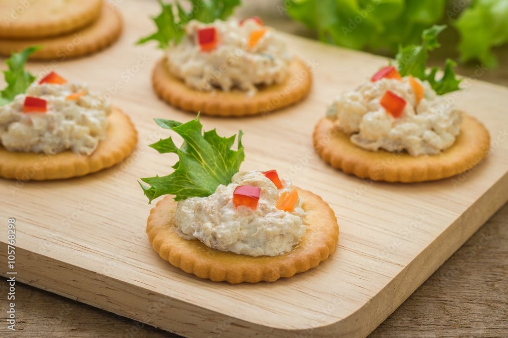 Crackers with tuna salad on wooden plate