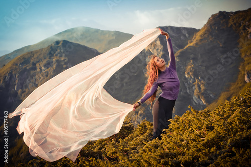 Girl with the light pink fabric playing with wind on mountains