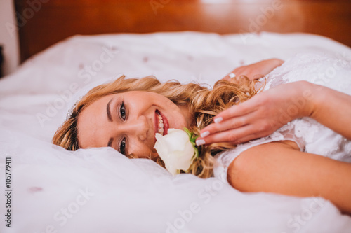 Beautiful woman in a wedding dress. She is in the bedroom with luxurious interior