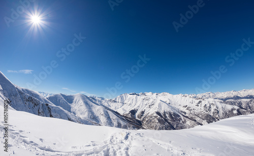 Sun star glowing over snowcapped mountain range, italian Alps