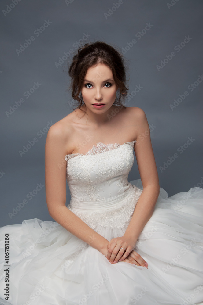 Adorable young bride with brown curly hair sitting in a cloud of Adorable young bride with brown curly hair sitting in a cloud of