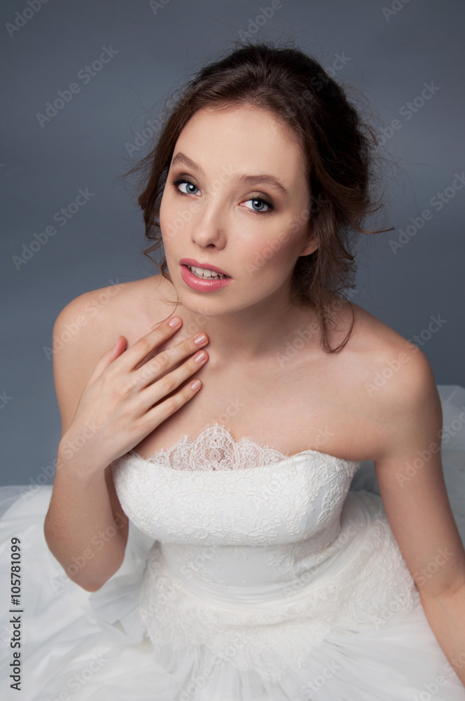 Adorable young bride with brown curly hair sitting in a cloud of Adorable young bride with brown curly hair sitting in a cloud of