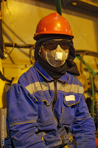 The worker in overalls and a respirator