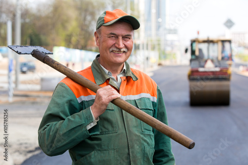 Vászonkép Portrait happy male road construction worker with asphalt pavement scraper tool