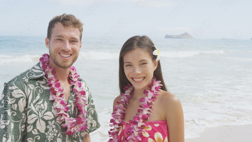 Happy Hawaii beach couple in Aloha Hawaiian shirt. Portrait of Asian woman and Caucasian man on beach standing with flower leis and typical attire for their wedding or honeymoon. RED EPIC SLOW MOTION. Happy Hawaii beach couple in Aloha Hawaiian shirt. Portrait of Asian woman and Caucasian man on beach standing with flower leis and typical attire for their wedding or honeymoon. RED EPIC SLOW MOTION.