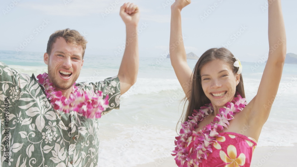 Cheering celebrating winning couple on Hawaii beach beach on Hawaiian vacation. Asian woman and Caucasian man wearing flower lei garland and Aloha clothing raising arms up dancing of joy. RED EPIC. Cheering celebrating winning couple on Hawaii beach beach on Hawaiian vacation. Asian woman and Caucasian man wearing flower lei garland and Aloha clothing raising arms up dancing of joy. RED EPIC.