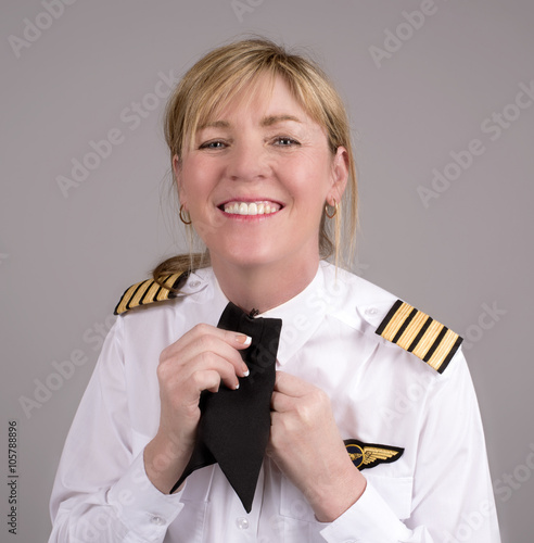 Canvas Print Senior female airline captain clipping her uniform cravat onto her shirt