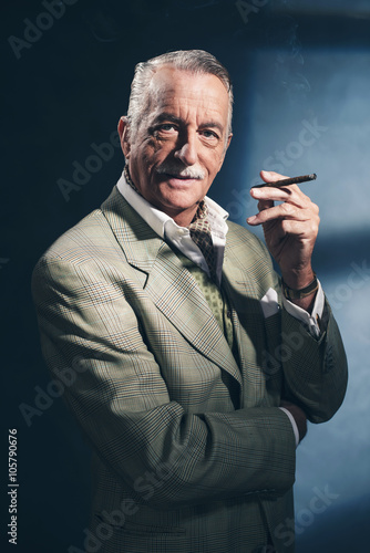 Cigar smoking retro 1940 senior businessman. Studio shot.