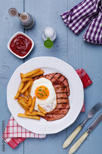 English breakfast with grilled ham, fried egg and french fries.
