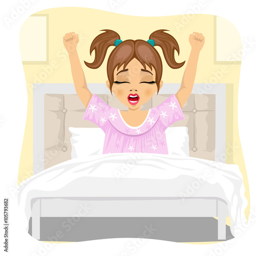 little girl lying waking up stretching and yawning lying on bed