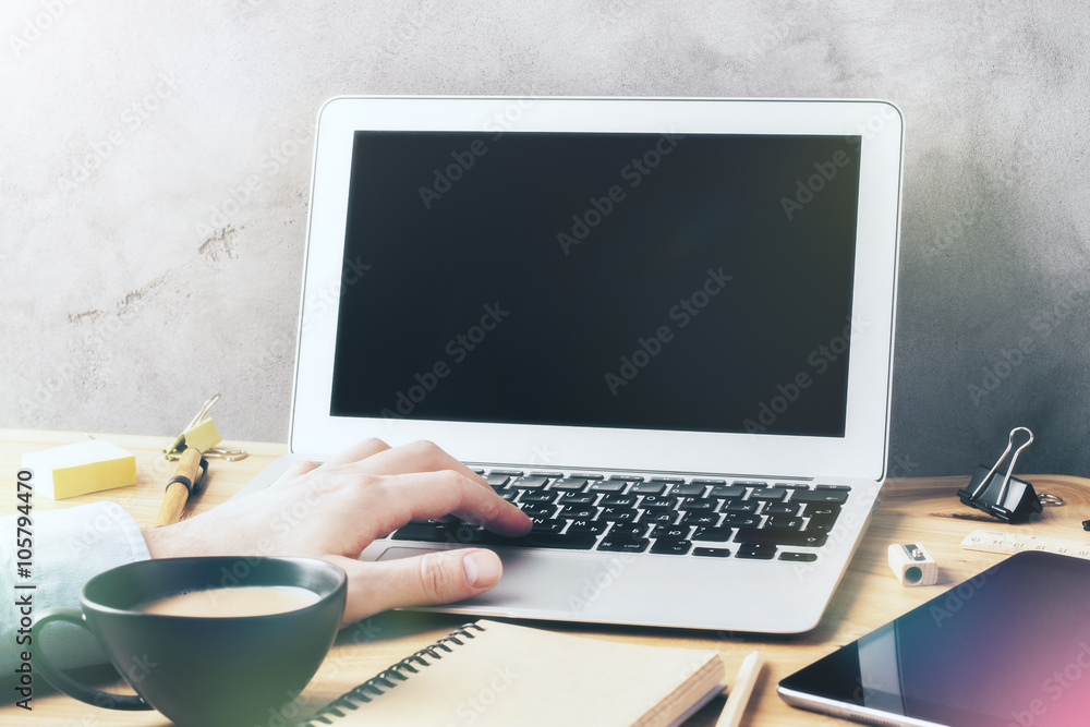 Fototapeta premium Man working with a laptop on a wooden table with a cup of coffee