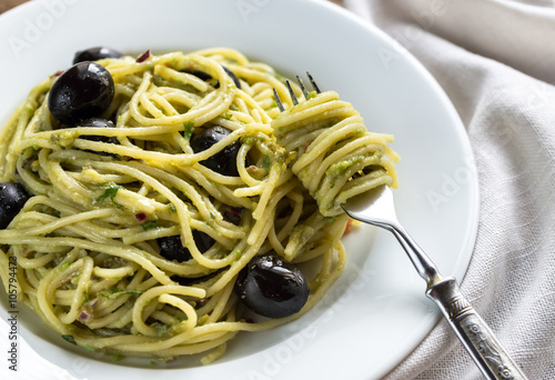 Pasta with guacamole sauce and black olives
