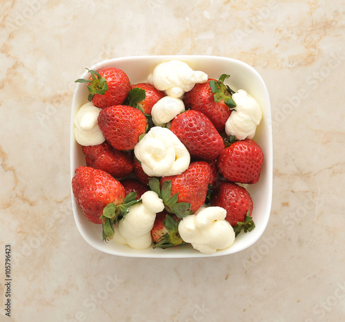 strawberry with cream in a white plate on a marble background. t
