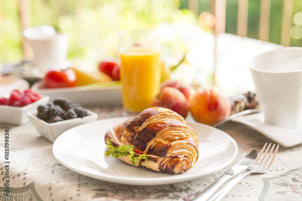 breakfast on the terrace, sandwich on the plate, glass of orange juice, peches in the background