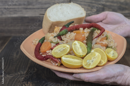 Foto Manos presentando plato de Arroz picante y trozo de pan, con pimiento de chile y