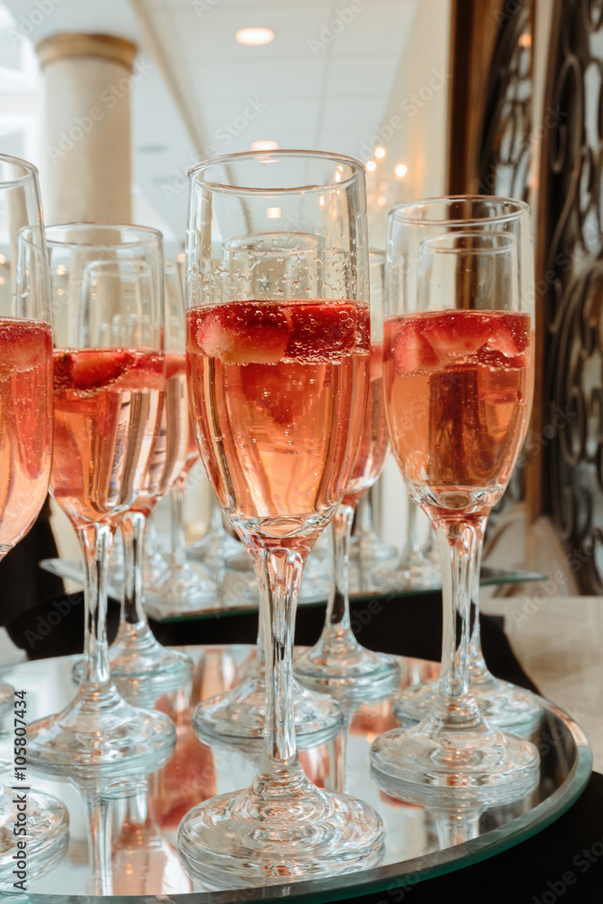Festive champagne flutes filled with sparkling wine and floating strawberries romantic twinkling party lights Festive champagne flutes filled with sparkling wine and floating strawberries romantic twinkling party lights