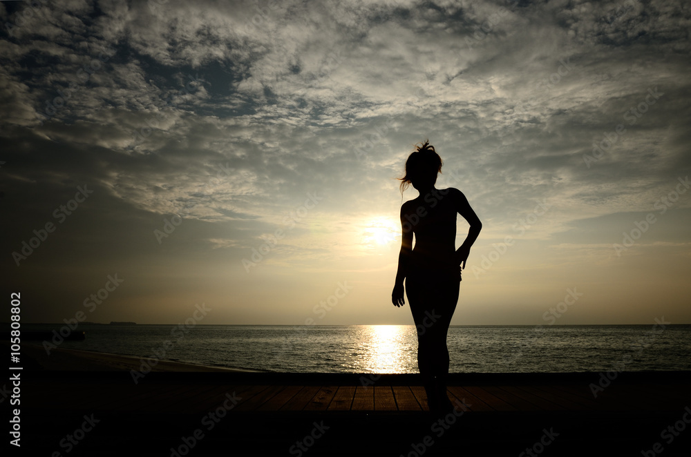 ビーチに立つシルエットの女性