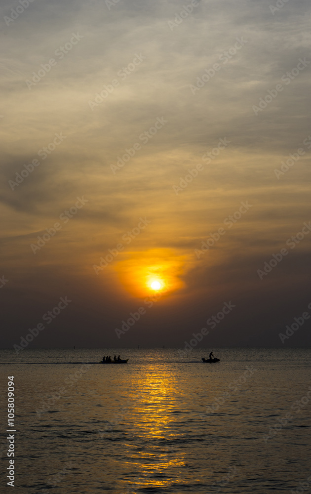 Group of people riding banana boat into the sea with sunset