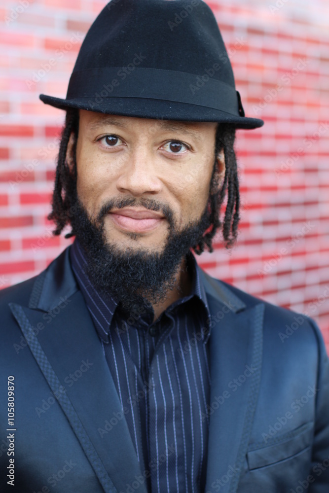 Vertical image of stylish African man wearing a suit and a hat on a bright and modern red background Vertical image of stylish African man wearing a suit and a hat on a bright and modern red background