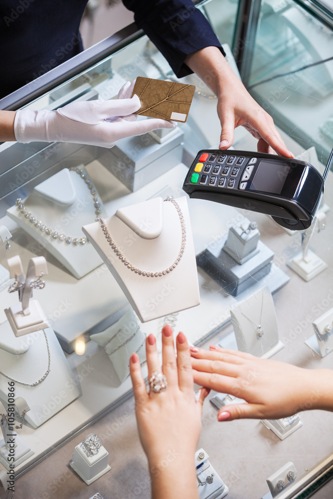 Fototapeta premium Young woman buying a golden ring and paying with a credit card