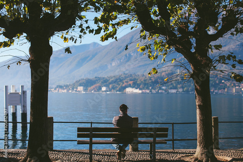 man sitting back on a bench with a view of Lake Como